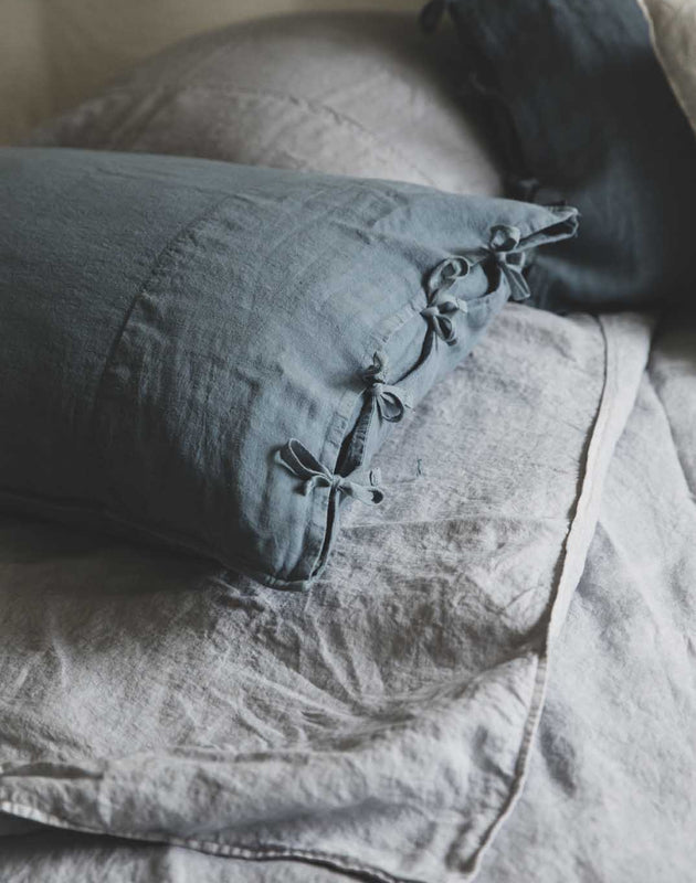 Linge de lit : drap en lin lavé gris avec les taies d'oreiller bleues