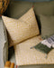 Housse de coussin Tulipan à motifs Curcuma sur un canapé vert