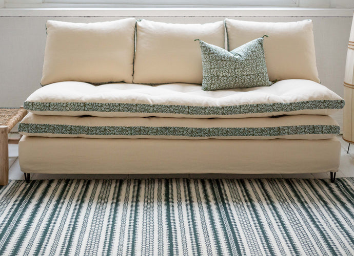 Canapé blanc avec des imprimés végétaux verts autour des coussins