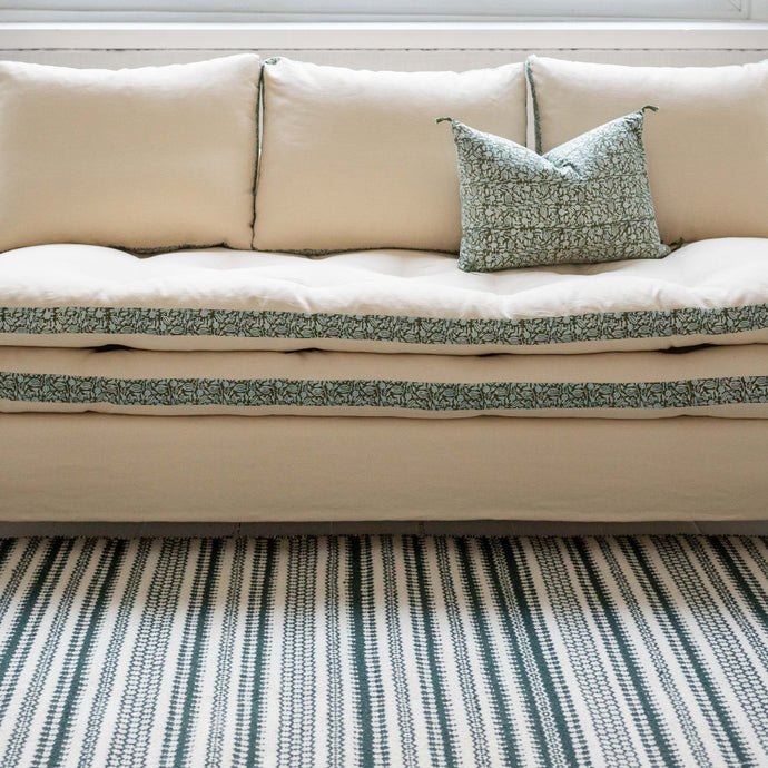 Canapé blanc avec des imprimés végétaux verts autour des coussins