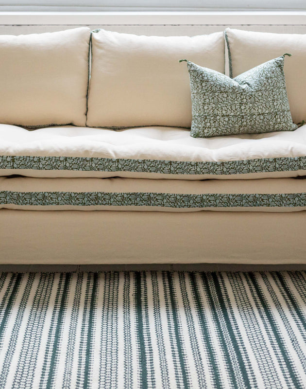 Canapé blanc avec des imprimés végétaux verts autour des coussins