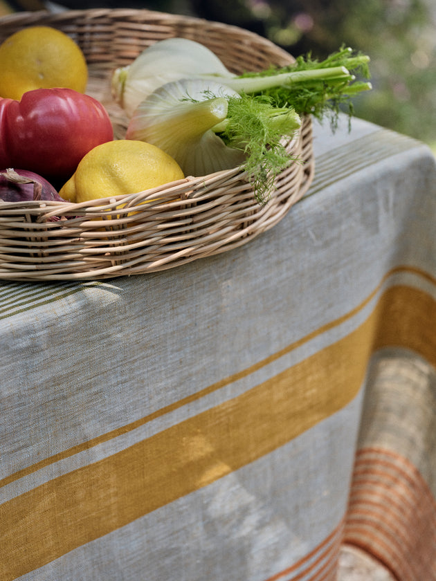 Détail des rayures de la nappe Soleo en lin sur laquelle est posée la cloche Salva en osier