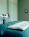 Chambre bleue avec du linge de lit Selena en lin lavé et une courtepointe en bout de lit
