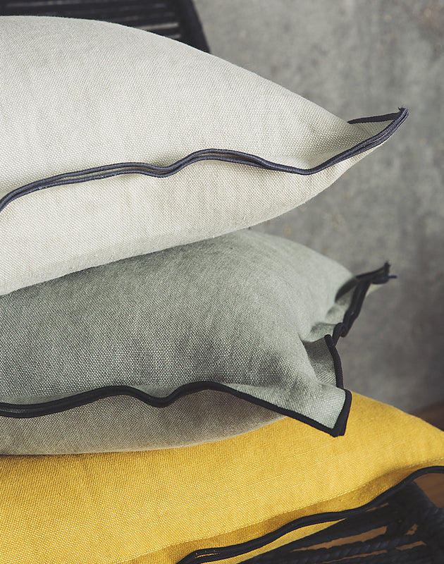 Housse de coussin en lin avec un bord noir en blanc, sage et moutarde