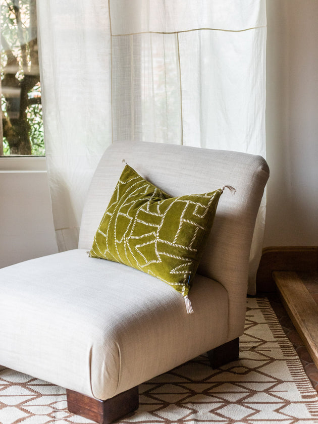 Un coussin Jody couleur Citrine posé sur un fauteuil chauffeuse Pacha