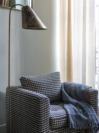 Lampadaire Ella bronze en acier à côté du fauteuil Stella