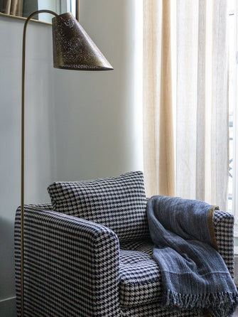Lampadaire Ella bronze en acier à côté du fauteuil Stella