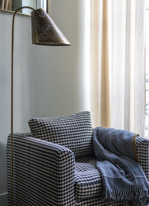 Lampadaire Ella bronze en acier à côté du fauteuil Stella