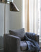 Lampadaire Ella bronze en acier à côté du fauteuil Stella
