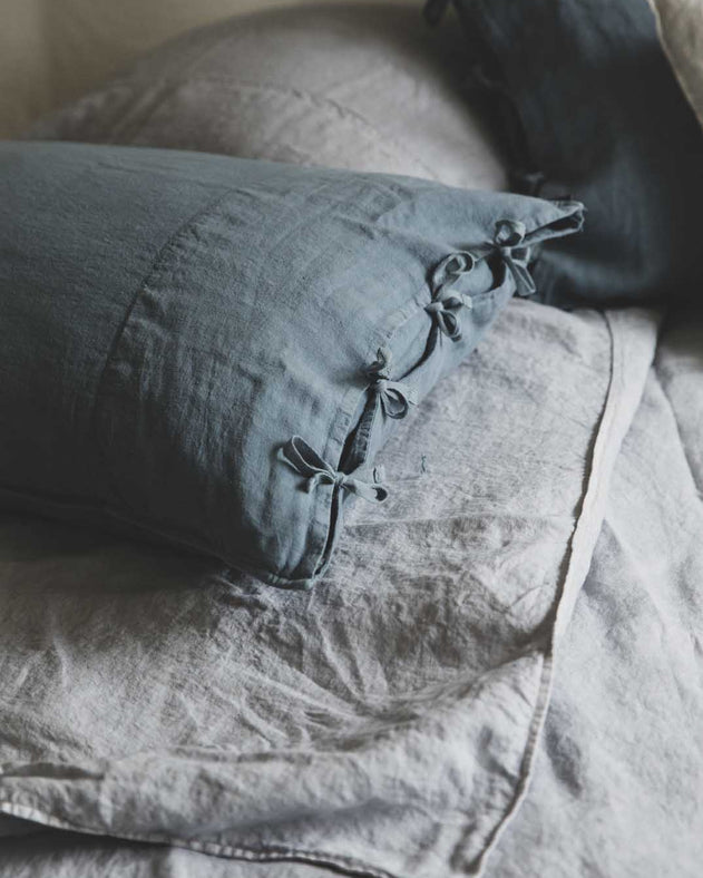 Linge de lit : drap en lin lavé gris avec les taies d'oreiller bleues