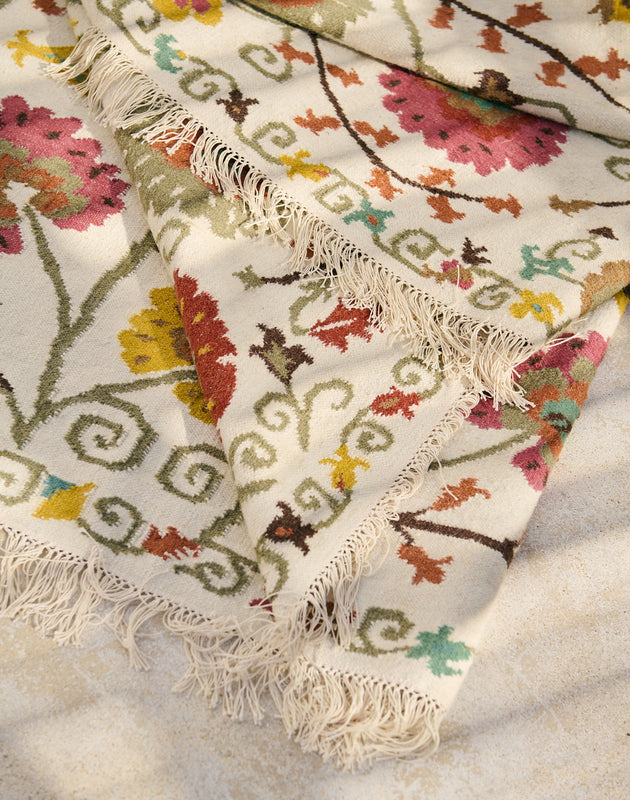 Détail des franges et des motifs fleuris du tapis Lohdi en laine