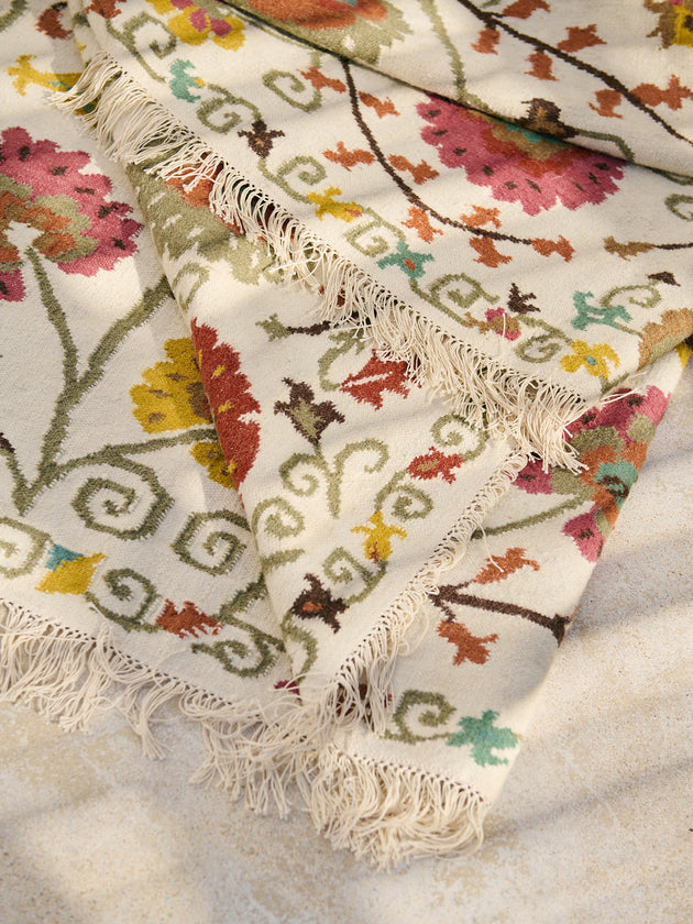 Détail des franges et des motifs fleuris du tapis Lohdi en laine