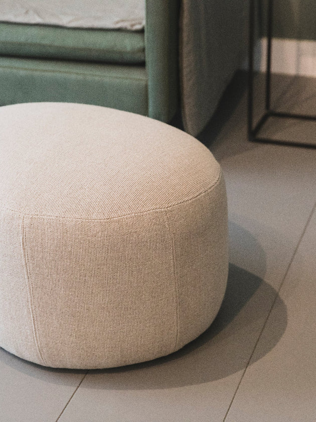 Petit pouf rond en tissu clair pour salon 